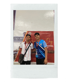 two young men are posing for a photo in front of a sign that says state university