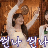 a woman is raising her arms in the air while holding a microphone in front of a clock ..