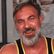a man with a beard wearing a yellow tank top is smiling