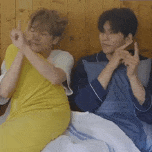 two young men are sitting next to each other on a bed making funny faces .