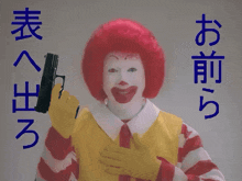 a mcdonald 's clown is holding a gun with chinese writing behind him