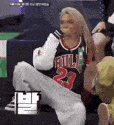 a woman wearing a bulls jersey sits on a bench