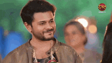 a man with a beard is smiling in front of a sign that says ' dangal tv '
