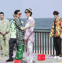 a group of people are standing on a deck with a red dice in the foreground