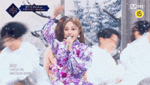 a woman in a purple dress is singing into a microphone while dancing on a stage .