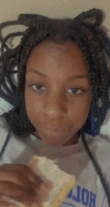 a girl with braids is eating a sandwich and wearing a shirt that says hort