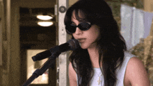 a woman singing into a microphone with sunglasses on