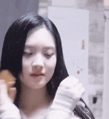 a woman with long black hair is brushing her hair with a comb .