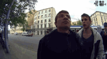 two men standing on a street with ed art tv written on the bottom right