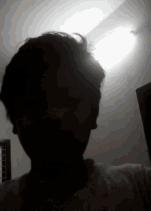 a person taking a selfie in the dark with a light behind them