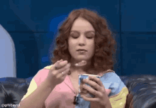 a woman sitting on a couch eating ice cream with a spoon