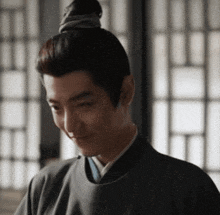 a man with a bun on his head is looking down