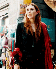 a woman in a black top and red scarf stands in front of a sign that says ' a ' on it