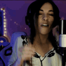 a woman is singing into a microphone with her eyes closed