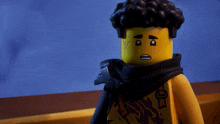 a yellow lego figure with black hair and a scarf around his neck looks at the camera