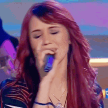 a woman with red hair sings into a microphone