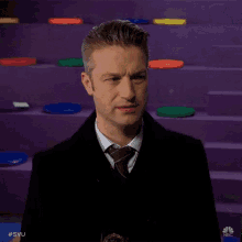 a man in a suit and tie is standing in front of a purple staircase with colorful frisbees on it ..