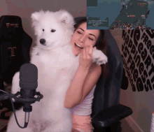 a woman is holding a white dog in front of a microphone with a screen behind her that says ' secret lab '