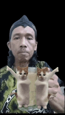 a man is holding a glass with two cats on its arms