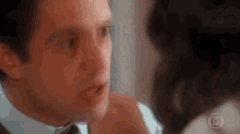a man in a suit and tie is looking at a woman in a white shirt .