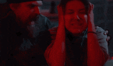 a man is holding a woman 's head in a dark room with a red light behind them .