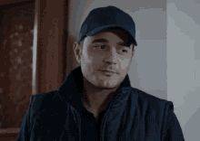 a man wearing a hat and a vest looks to the side