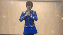 a man in a blue jacket is standing in front of a white wall
