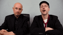 two men in suits and ties are sitting next to each other