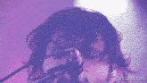 a close up of a person singing into a microphone with the website gifrun.com visible
