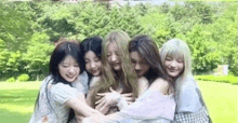 a group of young women are hugging each other in a field .