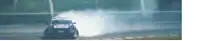 a car is drifting on a race track and smoke is coming out of it 's tires .