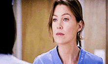 a close up of a woman wearing a blue scrub top looking at a man .
