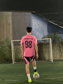 a soccer player in a pink shirt with the number 98 on it