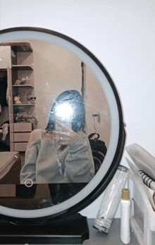 a woman is taking a selfie in a round mirror