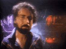 a blurry picture of a man with a beard wearing a blue jacket with the letter a on it