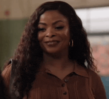 a woman wearing a brown shirt and earrings is smiling and looking at the camera .