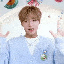 a young man wearing a light blue cardigan has a pin on his sweater that says ' i love you '