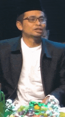 a man wearing glasses and a hat is sitting in front of a table