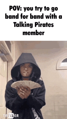 a man in a hoodie is holding a bunch of money in his hands