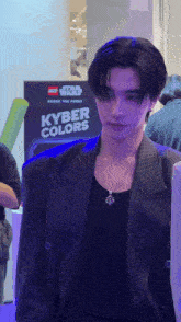 a man in a suit stands in front of a sign that says " kyber colors "