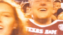 a man wearing a texas army jersey is laughing in a crowd