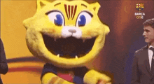 a man in a suit stands next to a yellow cat mascot