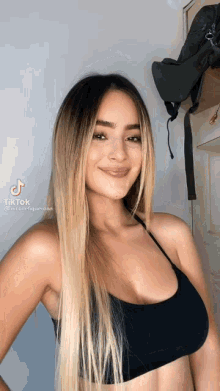 a woman is wearing a black bra and smiling at the camera .