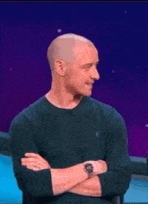 a man with his arms crossed and a watch on his wrist smiles