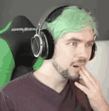 a man with green hair is wearing headphones .