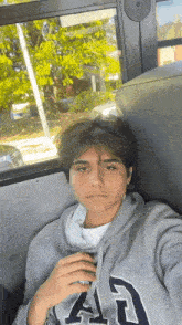 a young man sitting on a bus wearing a gray gap hoodie