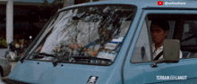 a man is driving a blue van with a sticker on the windshield that says ' astroshaw ' on it