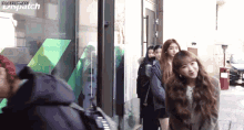 a group of girls are standing in front of a building with dispatch written above them
