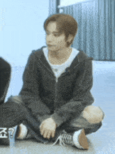 a young man is sitting on the floor with his legs crossed