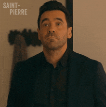 a man in a suit is standing in front of a sign that says saint pierre